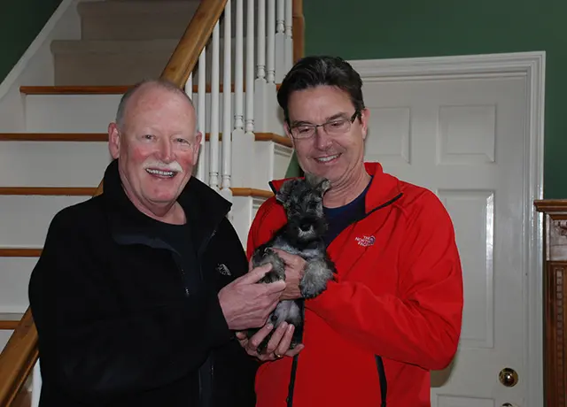 Two men holding a cat in their hands.